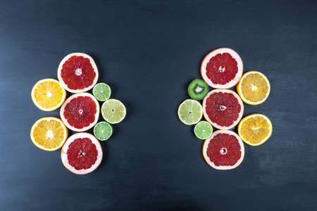 Creative arrangement of slices of citrus fruits on black painted surface. Top view with copy space.の写真素材