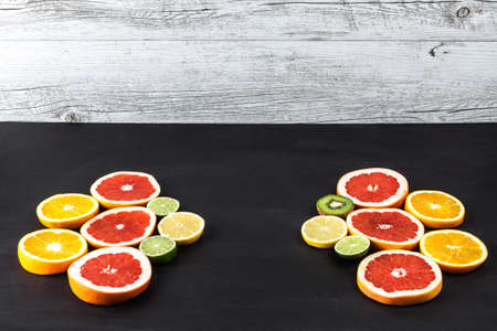 Creative arrangement of slices of citrus fruits on black painted table with copy space.の写真素材
