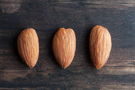 Three almonds on rustic wooden table closeup with copy spaceの写真素材