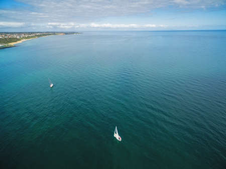Aerial image of two sailboats sailing turquoise watersの写真素材