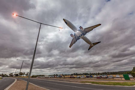 Melbourne, Australia - January 2, 2017:  Passenger jet airplane flying low in the sky right above glowing street lights in stormy weatherのeditorial素材