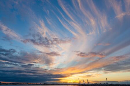 Port cranes silhouettes in beautiful golden glowing sunset in Melbourne, Australiaの写真素材