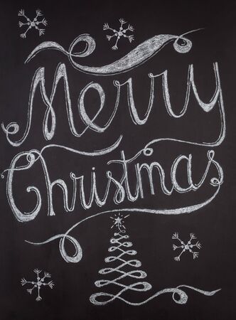 Merry Christmas hand drawn lettering with chalk on blackboard. Elegant unique design with snowflakes and Christmas treeの写真素材