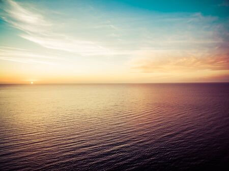 Aerial view of sun setting over ocean. Nothing but skies and water. Beautiful tranquil sceneの写真素材
