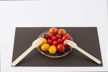 Various colored cherry tomatoes and two forks culinary composition isolated on whiteの写真素材