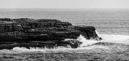 Ocean waves breaking on rugged coastal cliffs. Black and white landscapeの写真素材