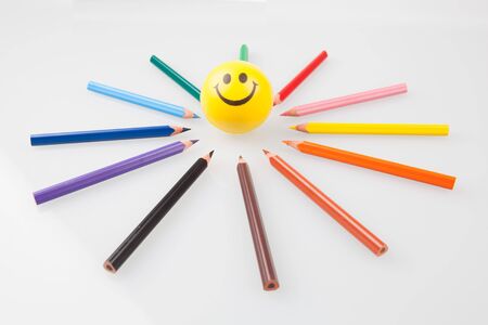 Sharp colorful pencils pointing at smiley face.の写真素材