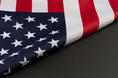 Folded fragment of American flag on black chalkboard. Horizontal image with diagonal copy space.の写真素材