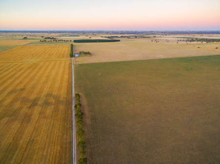 Harvested agricultural field and pastures at sunset in rural Australia aerial viewの写真素材