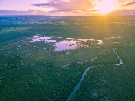 Aerial view of sun setting over horizon above mangroves and river. Melbourne, Australia