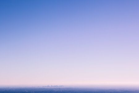 Small silhouette of Melbourne CBD skyscrapers in urban fog with lots of blue sky for copy space