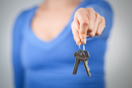 Woman holding home keys in front of her body. Focus on foregroundの写真素材