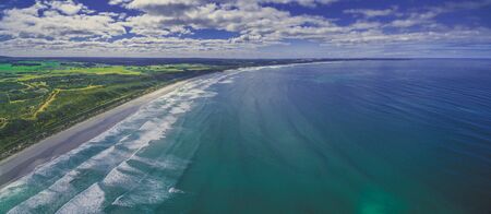Aerial panorama of beautiful ocean coastline, white sandy beach, and farm lands in Australia