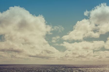 Fluffy clouds and calm ocean water. Image has retro filter appliedの写真素材
