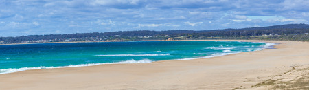 Beautiful ocean beach on bright sunny day with white fluffy clouds panoramaの写真素材