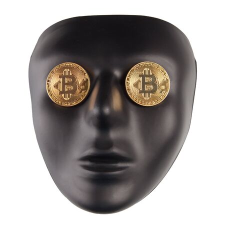 Black face mask with golden bitcoins placed on eyes isolated on white. Anonymity and cryptocurrency conceptの写真素材