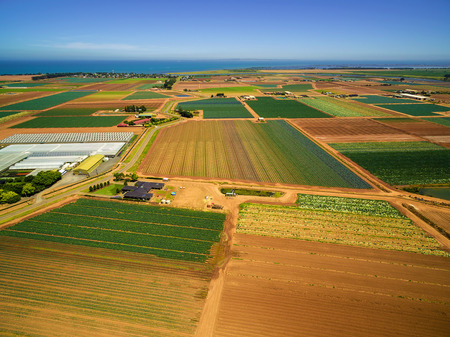 Aerial scenic view of agricultural fields near ocean coastline in Australia