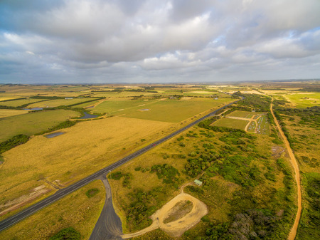 Aerial scenic landscape of rural road passing through pastures and meadows in Australiaの写真素材
