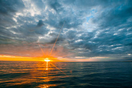 Minimalist seascape - overcast clouds over calm ocean waters at sunsetの写真素材