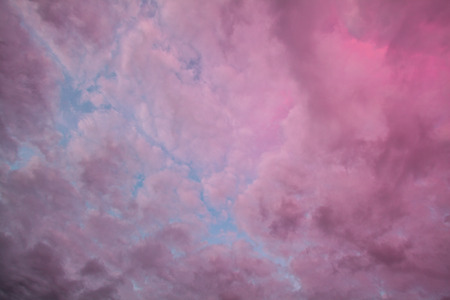 Looking straight up at clouds colored purple by the sunsetの写真素材