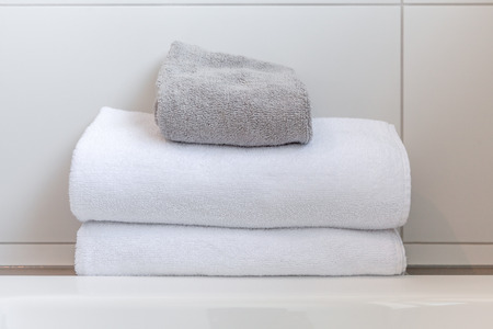 White and gray folded towels against white tiles in bathroomの写真素材