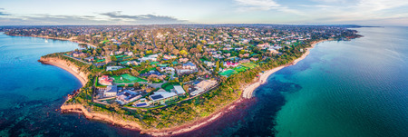 Large aerial panorama of coastline with luxury villas and suburban area at sunsetの写真素材
