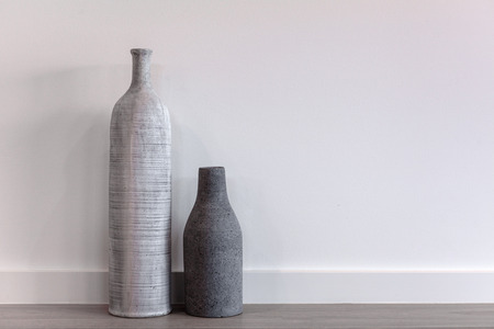 Two decorative modern vases - long and short on wooden floor against white wall with copy spaceの写真素材