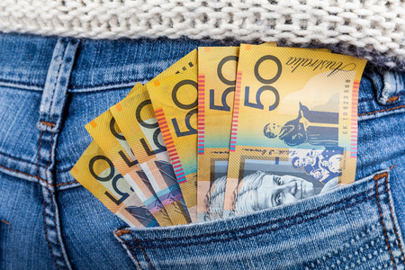 50 AUD bills in fan shape placed in female jeans back pocket closeup - minimum wage concept
