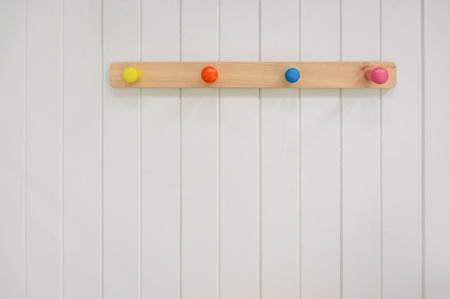 Kids wooden colorful hanger on white wall with copy spaceの写真素材
