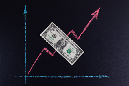 Upward trend chalk line graph drawing on blackboard with 1 USD bill on it and copy space. Finance and forex upward trend conceptの写真素材