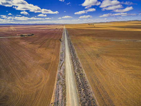 Straight dirt road leading to the horizon between plowed fields in Australian countrysideの写真素材