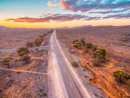 Rural road leading to the hills through desert at sunset - aerial viewの写真素材