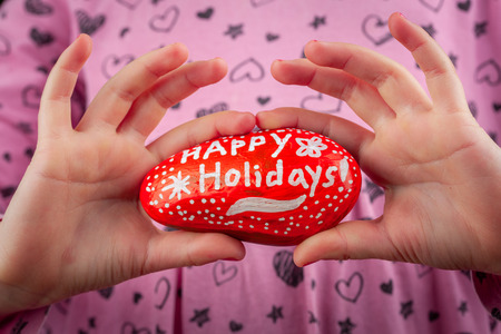 Girl showing red painted rock - Happy Holidays hand lettering greetings closeupの写真素材