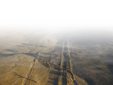 Straight rural road passing through Australian countryside and disappearing in low clouds - aerial viewの写真素材