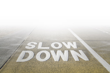 Big Slow Down sign on a footpath disappearing in white fog