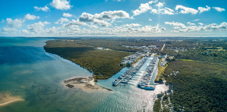 Moored boats and ocean coastline on bright sunny day - aerial panoramic landscapeのeditorial素材
