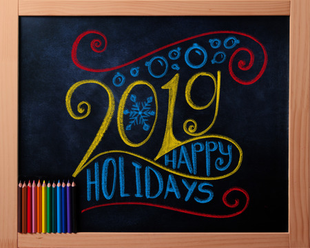 Happy Holidays 2019 colorful chalk lettering on blackboard with pencilsの写真素材