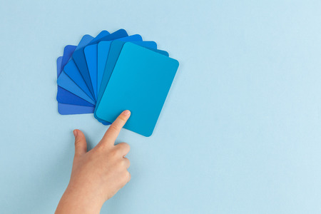 Child's hand pointing at color samples cards - hues of blue with copy spaceの写真素材