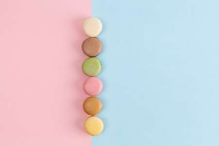 Row of colorful French macarons on pink-blue background with copy spaceの写真素材