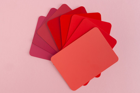 Color swatches sample cards spread in fan shape - hues of red with copy space