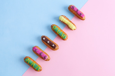Top view of French eclairs placed diagonally on blue and pink background with copy spaceの写真素材