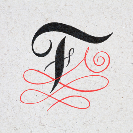 Calligraphic letter F with flourishes on kraft paperの写真素材
