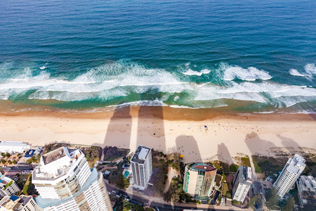 Long shadows on the beach from skyscrapers with people bathing - birds eye view. Gold Coast, QLD, Australiaの写真素材