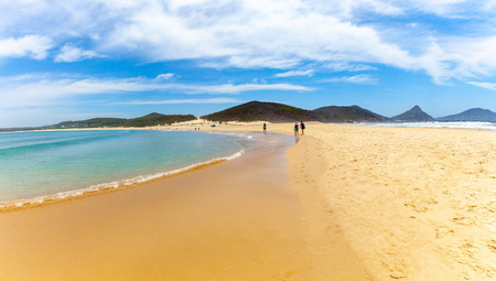 People walking on the beach towards Fingal Island at Fingal Bay, NSW, Australiaの写真素材