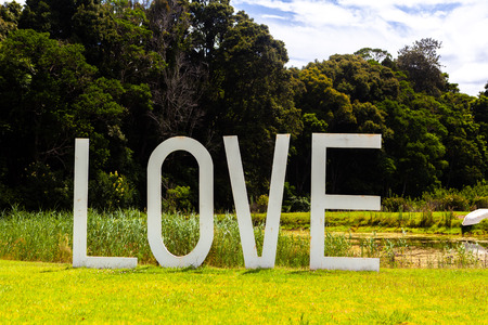 Big LOVE sign near a pond on green grass on bright sunny dayの写真素材
