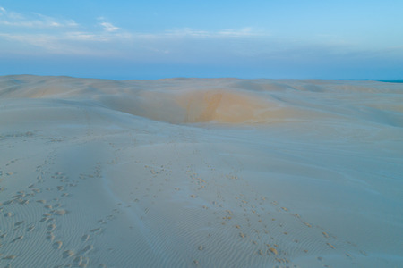 Footprints across sand dunes at dawn - aerial view.の写真素材