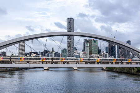 Train crossing the Merivale bridge over Brisbane river with modern high-rise in the backgroundの写真素材