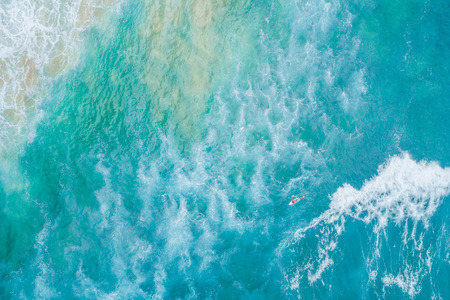 Surfer rowing on his surfboard toward ocean waves - aerial view with copy spaceの写真素材