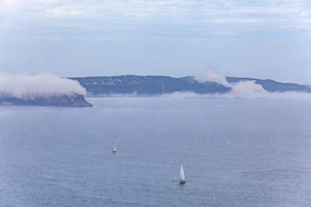 Two sailboats with white sails sailing across Broken Bay in Sydney, Australiaの写真素材