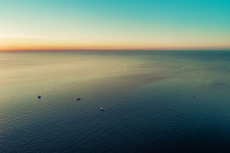 Small boats in vast sea at dusk - aerial view with copy spaceの写真素材